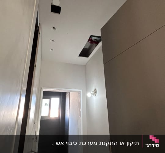 צינור וראש ספרינקלר הנראים דרך פתח בתקרת גבס במהלך עבודות התקנה